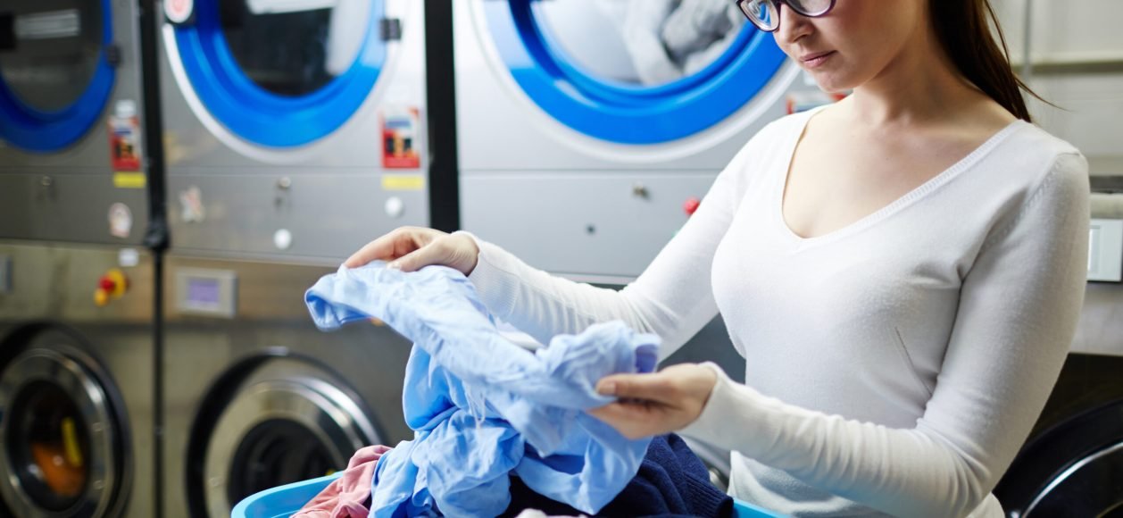 Woman looking at dirty shirt in laundry